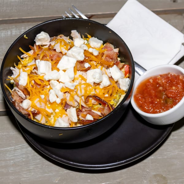 A breakfast bowl from Jude's Health and Java House with cheese, bacon, and feta, served with salsa.